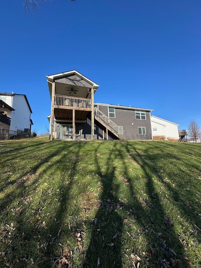 rear view of property with a deck, ceiling fan, and a lawn