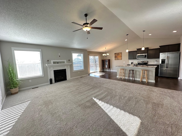 living room with dark colored carpet, ceiling fan with notable chandelier, a healthy amount of sunlight, and lofted ceiling