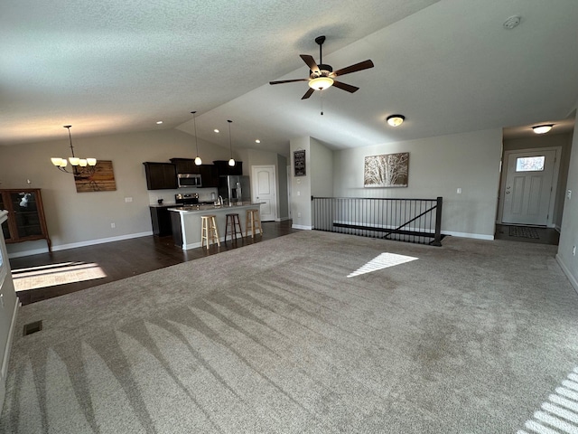 unfurnished living room with ceiling fan with notable chandelier, dark carpet, lofted ceiling, and a textured ceiling