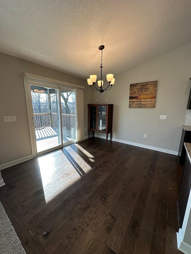 unfurnished dining area with vaulted ceiling, dark hardwood / wood-style flooring, a textured ceiling, and a chandelier