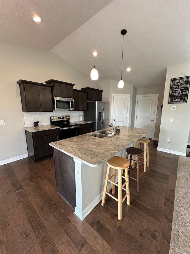 kitchen featuring tasteful backsplash, stainless steel appliances, a kitchen island with sink, sink, and pendant lighting