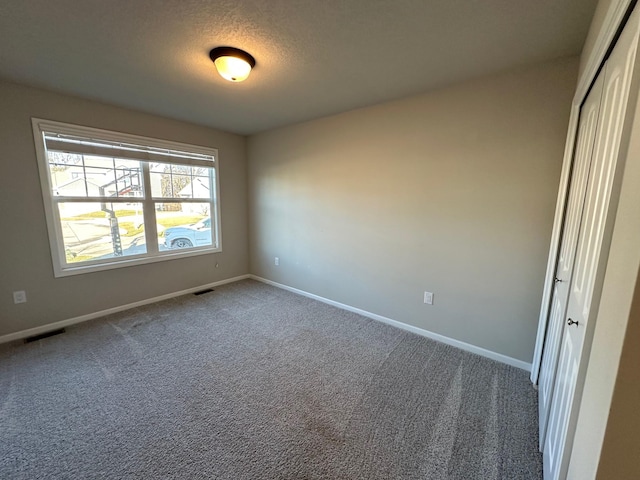 carpeted empty room featuring a textured ceiling