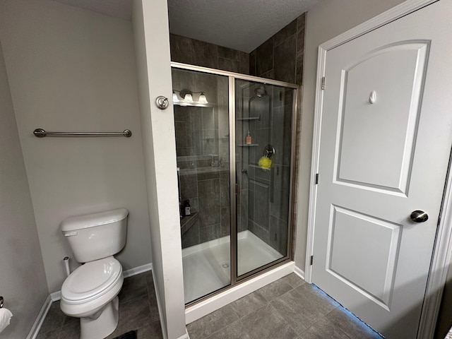 bathroom with an enclosed shower, toilet, tile patterned floors, and a textured ceiling