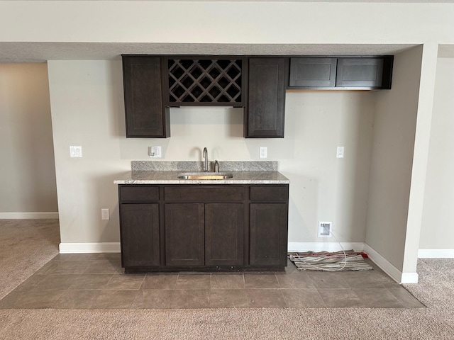 kitchen with carpet flooring, dark brown cabinetry, and sink