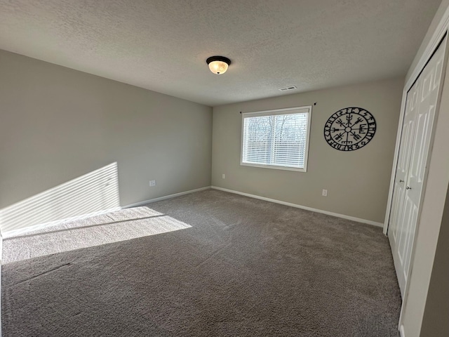 spare room with dark carpet and a textured ceiling