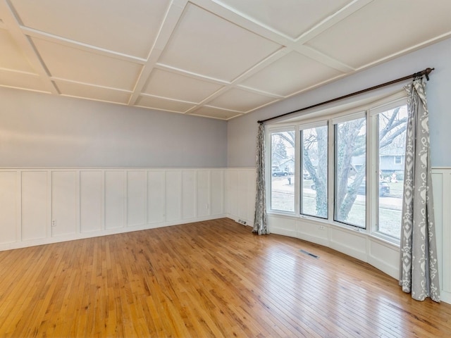 spare room featuring plenty of natural light, wood-type flooring, and coffered ceiling