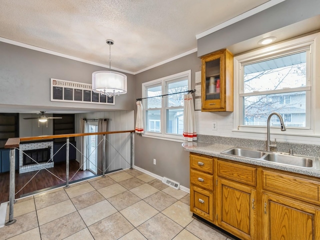 kitchen with sink, hanging light fixtures, light tile patterned floors, ceiling fan with notable chandelier, and ornamental molding