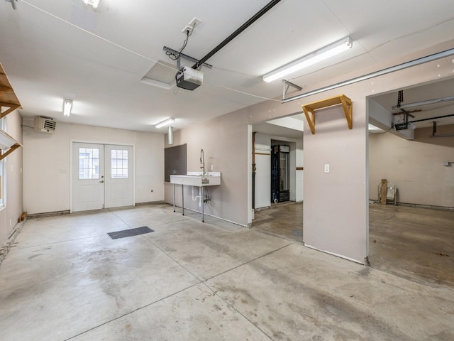 garage with french doors, a garage door opener, a wall mounted AC, and sink