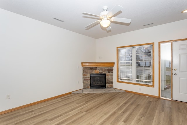 unfurnished living room featuring a fireplace, ceiling fan, and light wood-type flooring