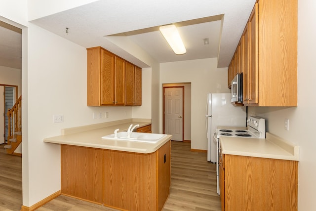 kitchen with sink, white electric range, light wood-type flooring, and kitchen peninsula