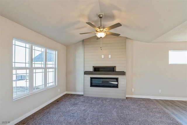 unfurnished living room featuring lofted ceiling, a fireplace, and a wealth of natural light