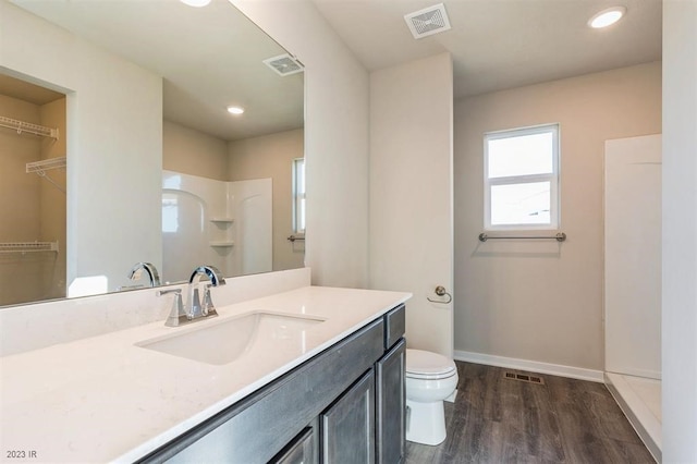 bathroom with walk in shower, wood-type flooring, toilet, and vanity