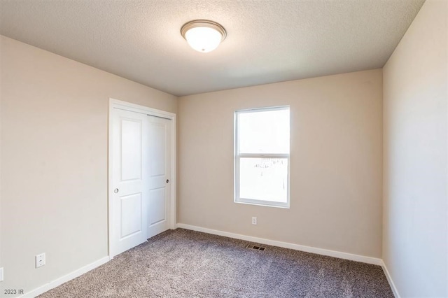 unfurnished bedroom with carpet floors, a closet, and a textured ceiling