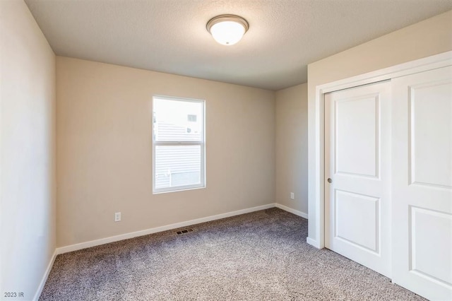 unfurnished bedroom with light colored carpet, a textured ceiling, and a closet