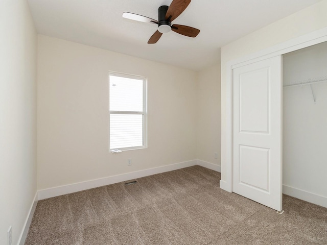 unfurnished bedroom featuring baseboards, light carpet, a ceiling fan, and a closet