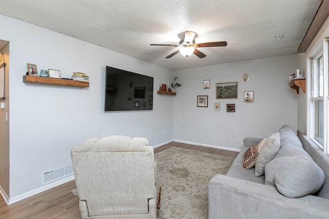 living room featuring ceiling fan, a textured ceiling, and hardwood / wood-style flooring