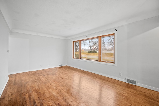 spare room featuring wood-type flooring and ornamental molding