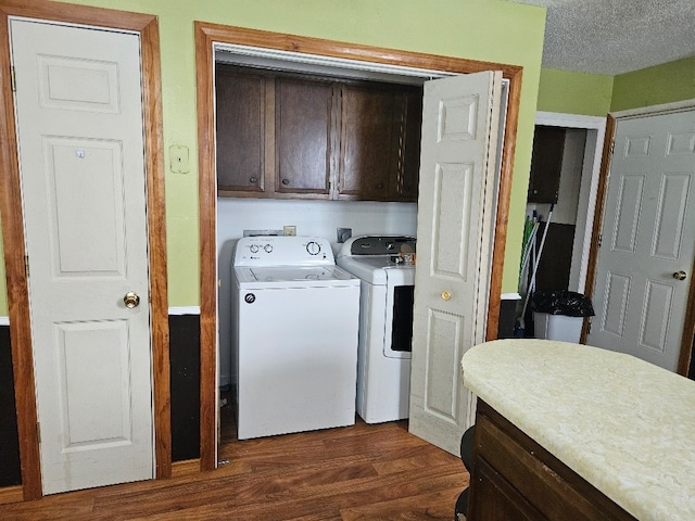 washroom featuring cabinets, a textured ceiling, washing machine and dryer, and dark wood-type flooring