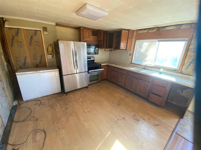 kitchen featuring sink, light hardwood / wood-style flooring, backsplash, appliances with stainless steel finishes, and ornamental molding