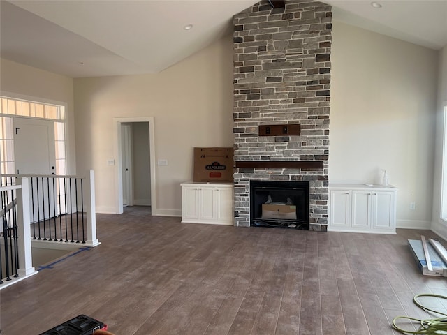 unfurnished living room with wood finished floors, a fireplace, baseboards, and high vaulted ceiling