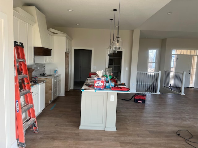 kitchen with decorative backsplash, a kitchen island, wood finished floors, and white cabinetry