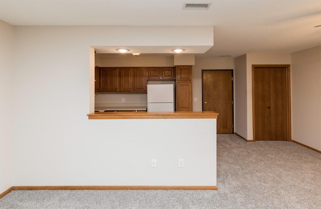 kitchen with white refrigerator and light colored carpet