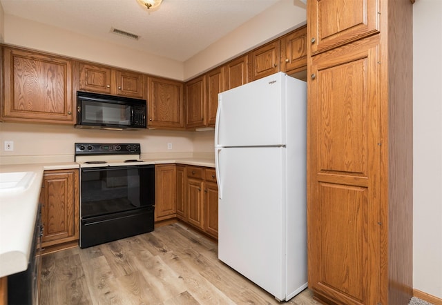 kitchen featuring sink, light wood-type flooring, white appliances, and a textured ceiling