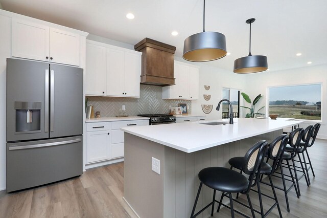 kitchen featuring white cabinetry, stainless steel fridge with ice dispenser, sink, and a kitchen island with sink