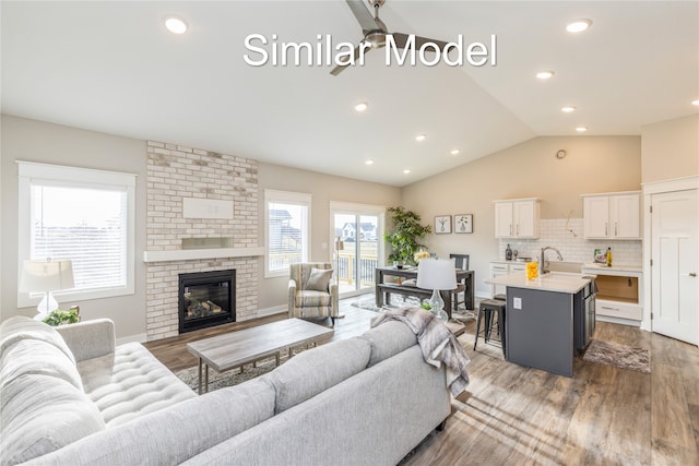 living room with a fireplace, hardwood / wood-style flooring, lofted ceiling, and sink