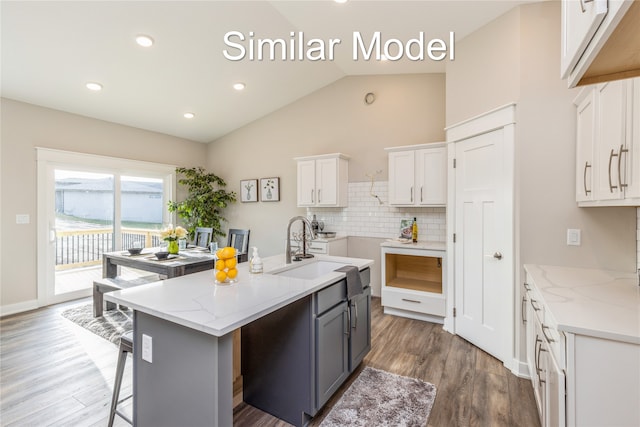 kitchen featuring lofted ceiling, a kitchen island with sink, dark wood-type flooring, sink, and white cabinetry