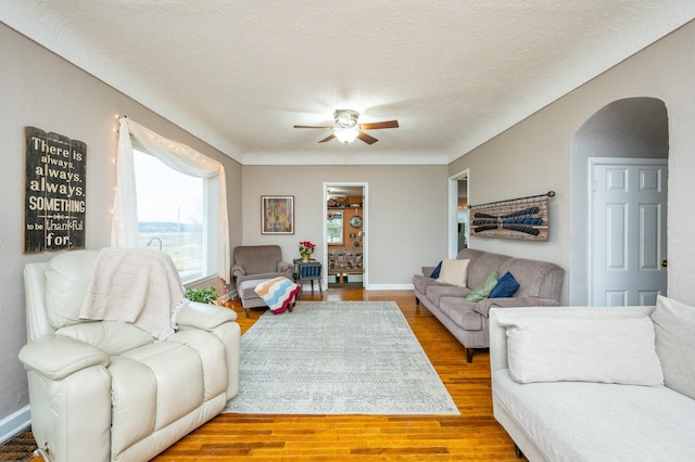 living room featuring ceiling fan, a textured ceiling, and hardwood / wood-style flooring