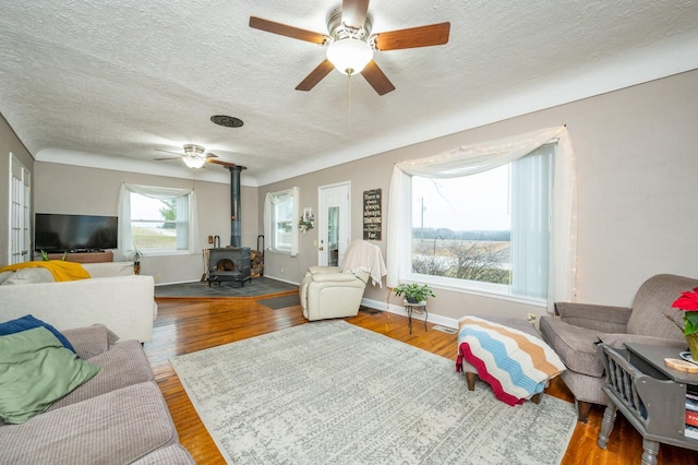 living room featuring a textured ceiling, a wood stove, and hardwood / wood-style flooring