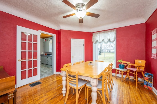 dining room featuring ceiling fan, wood-type flooring, and a textured ceiling