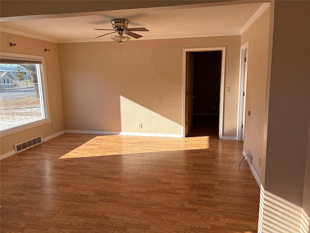 empty room with a textured ceiling, ceiling fan, hardwood / wood-style flooring, and ornamental molding