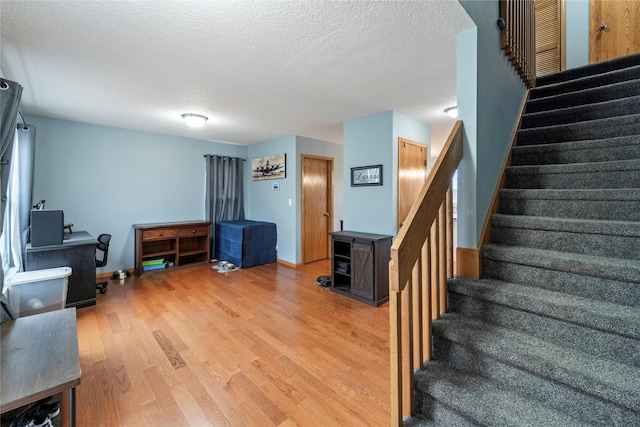 stairs with a textured ceiling and hardwood / wood-style flooring