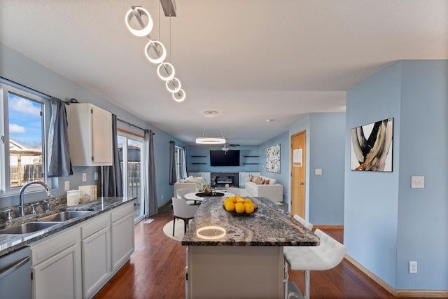 kitchen with white cabinetry, dark wood finished floors, a sink, dishwasher, and open floor plan