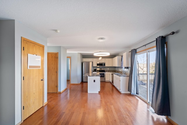 kitchen with a sink, a textured ceiling, light wood-style floors, and stainless steel appliances