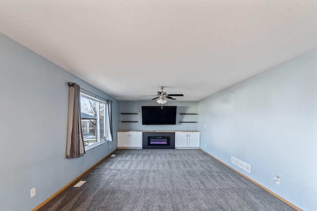 unfurnished living room with carpet, baseboards, visible vents, a ceiling fan, and a glass covered fireplace