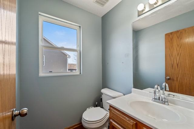 half bathroom featuring visible vents, toilet, and vanity