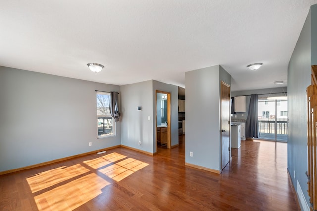 empty room featuring plenty of natural light, wood finished floors, and baseboards