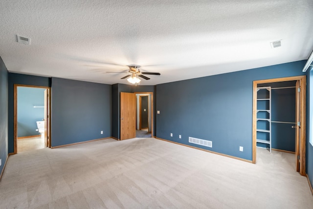 unfurnished bedroom with a spacious closet, carpet, visible vents, and baseboards