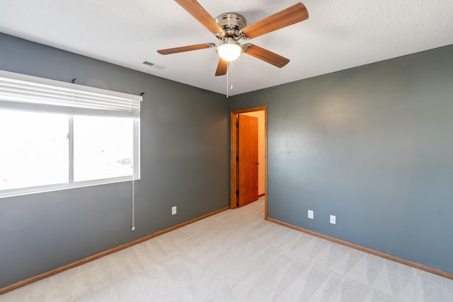 carpeted empty room featuring visible vents, baseboards, a textured ceiling, and ceiling fan