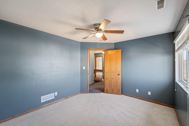 carpeted spare room with visible vents, ceiling fan, a textured ceiling, and baseboards