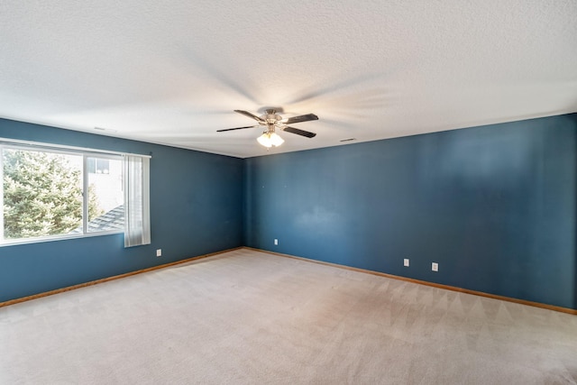 empty room with light colored carpet, a textured ceiling, baseboards, and ceiling fan