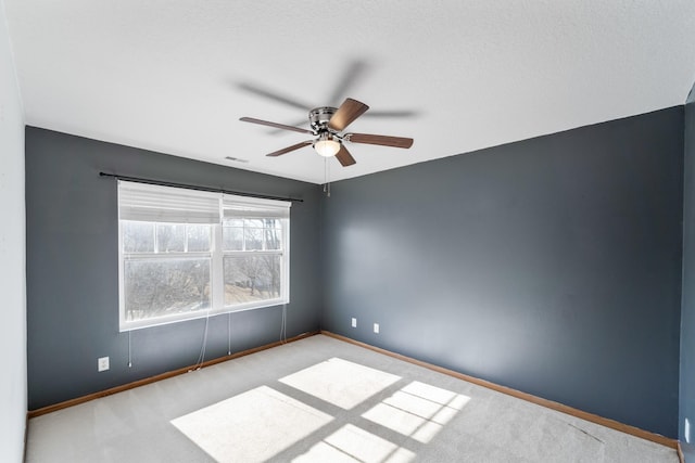 spare room featuring visible vents, baseboards, a ceiling fan, and carpet flooring