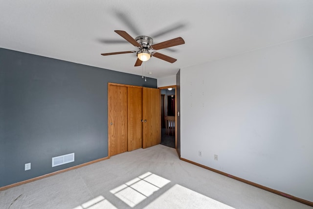 unfurnished bedroom with visible vents, light carpet, a closet, baseboards, and ceiling fan