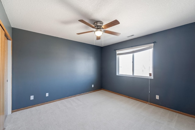 empty room with visible vents, carpet flooring, a textured ceiling, and baseboards