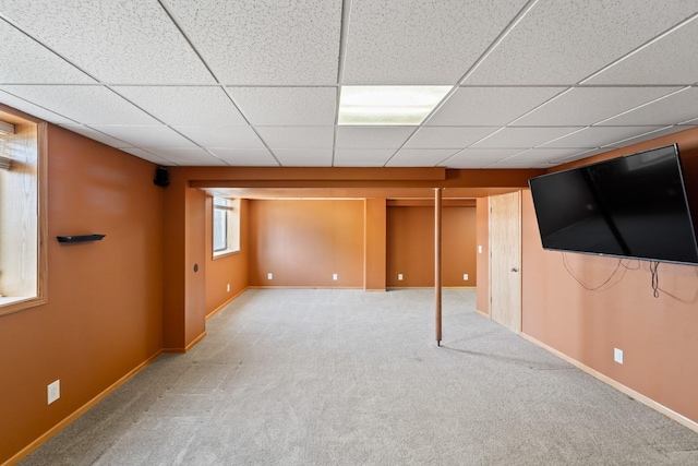 below grade area featuring carpet, baseboards, and a paneled ceiling