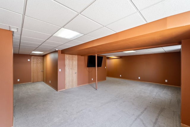 finished below grade area featuring carpet flooring, a paneled ceiling, and baseboards