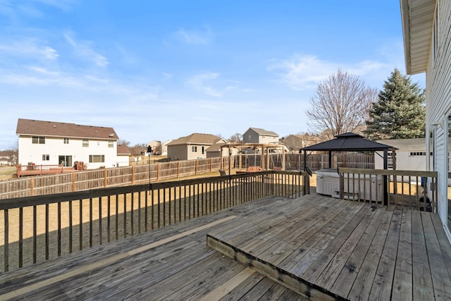 wooden deck featuring a gazebo, a residential view, and a fenced backyard